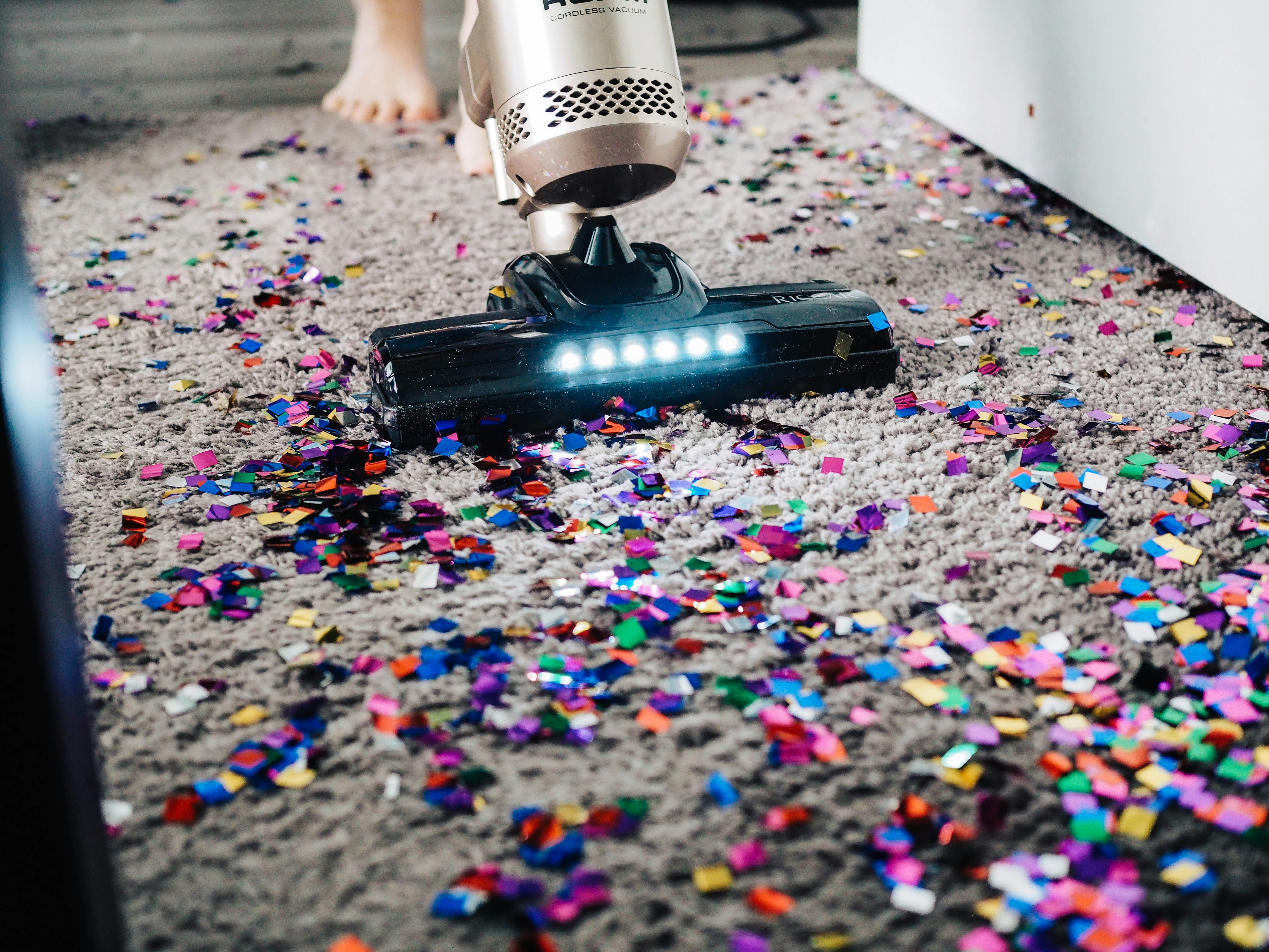 Vacuum cleaner cleaning colorful confetti from carpet after a party