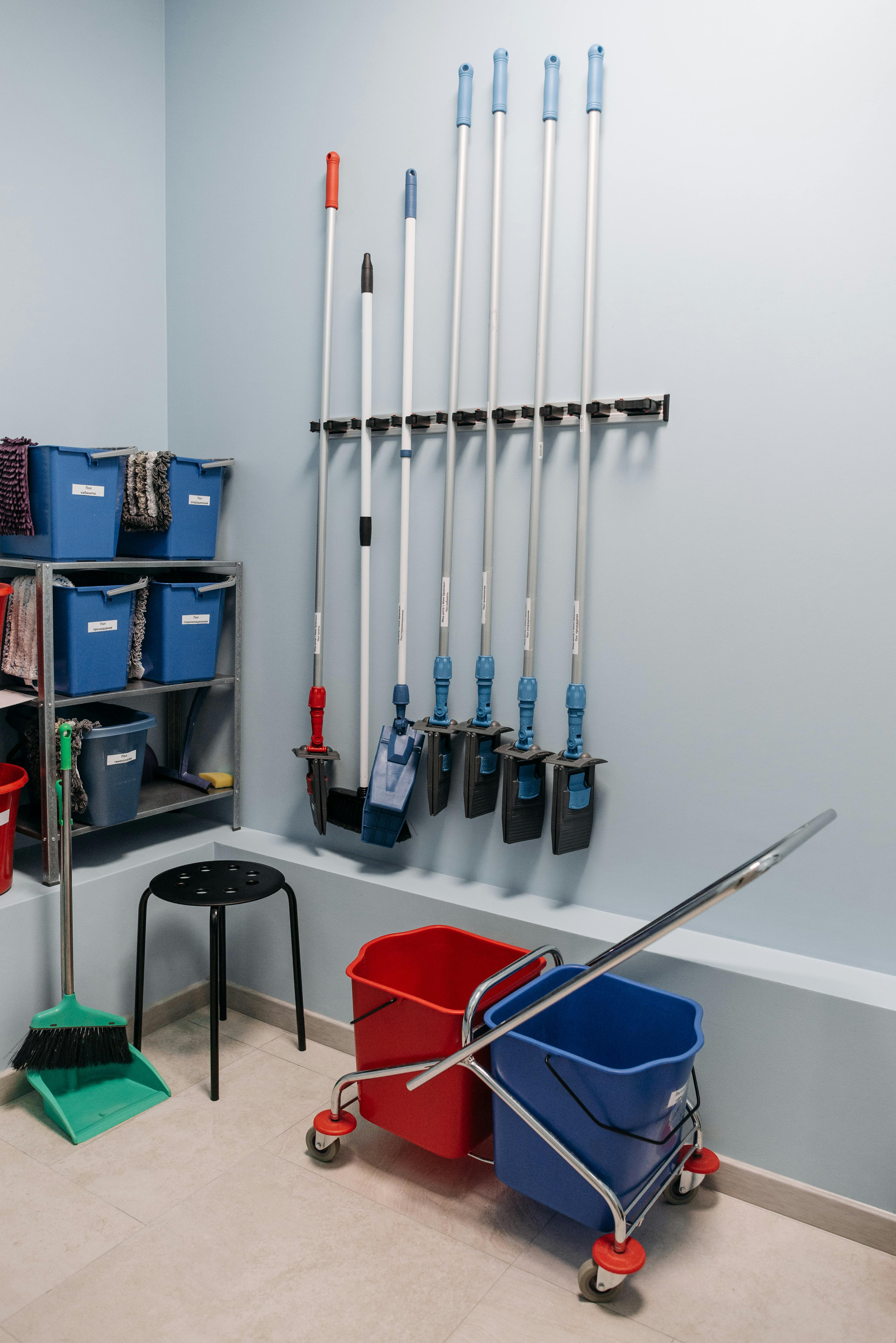 Professional cleaning equipment organized in a storage area with mops, buckets and cleaning supplies