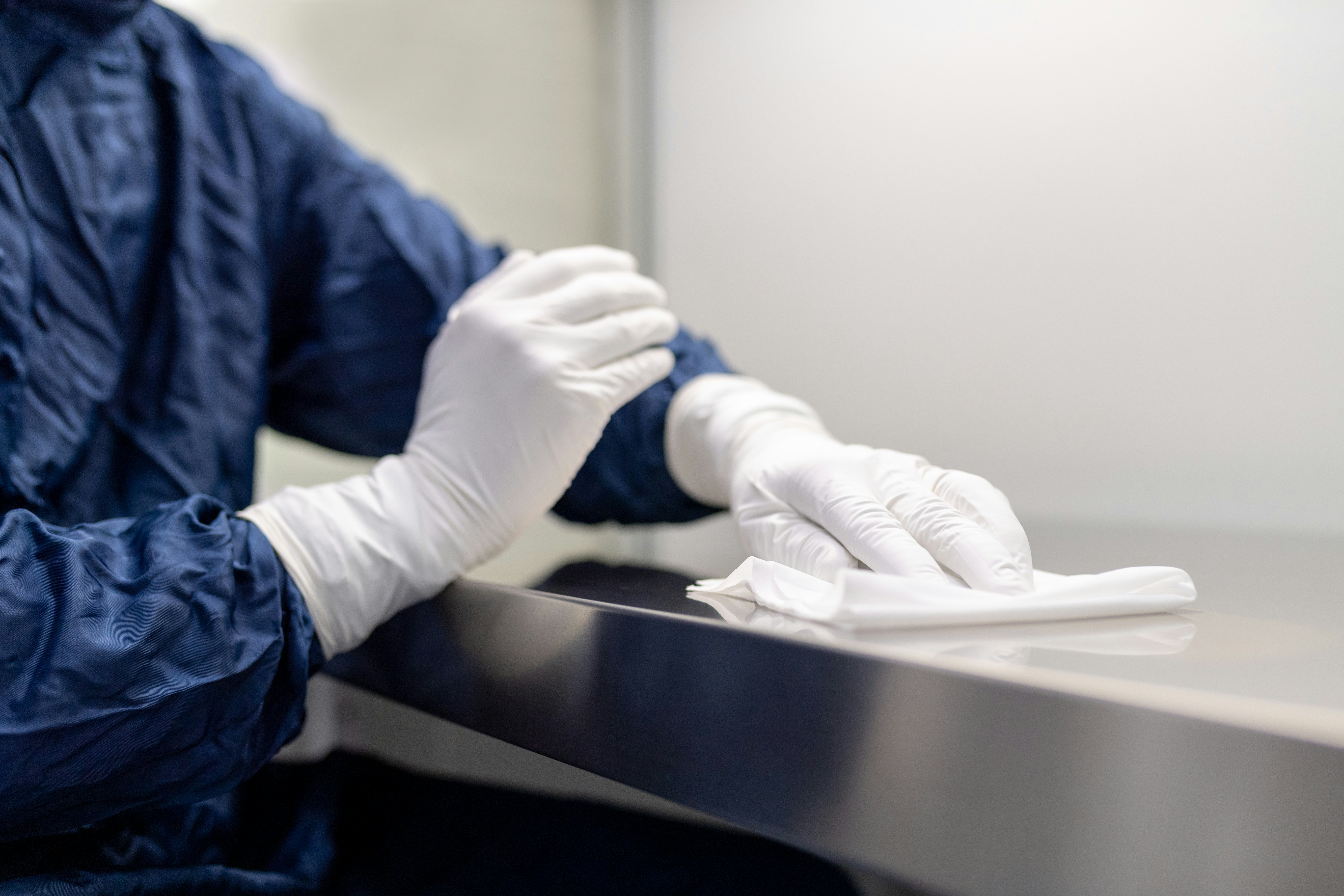 Professional cleaner with gloves sanitizing restaurant counter